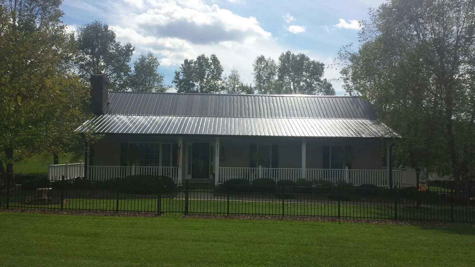 Gray metal roof on a brick ranch with a full width front porch — Gutter Guard Installation work by our crew in Bolton